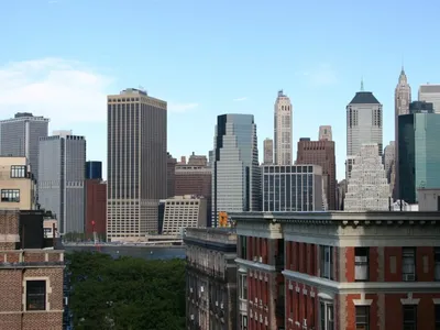 Lower Manhattan high-rises rising beyond older brick apartment rooftops