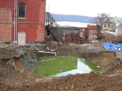 Bulk super-sacks of excavated soil staged on plastic sheeting beside a GCE service truck