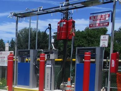 Fleet fueling island with FuelMaster dispensers, overhead piping, and fire-suppression cylinders