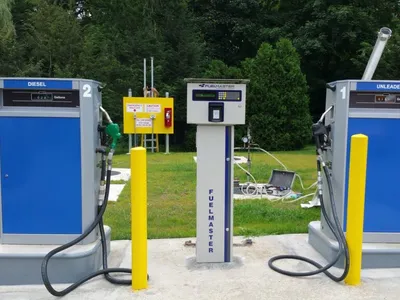 Blue diesel and unleaded dispensers with a FuelMaster control pedestal on a pad