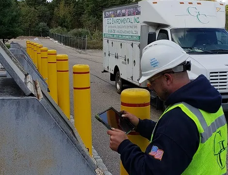 Inspector with a tablet checking bollards by a flammable liquids tank rack