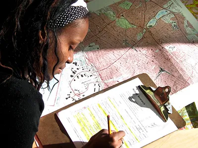 Worker marking findings on a clipboard over a topographic map