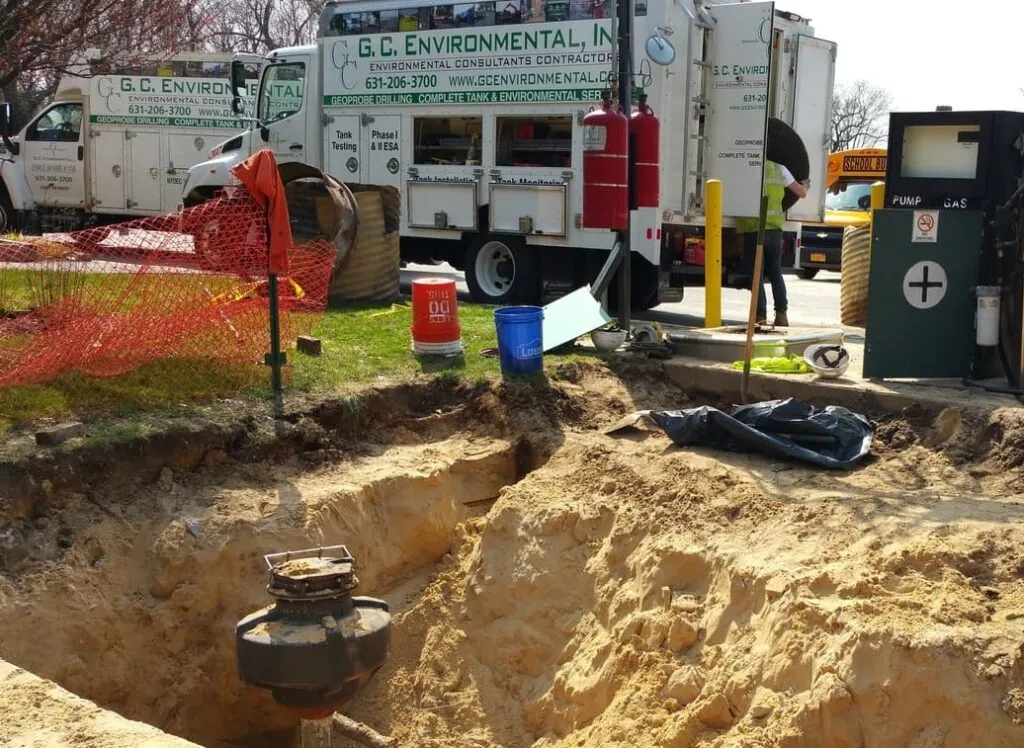 GCE service trucks beside an excavated pit exposing a tank sump and fuel dispenser