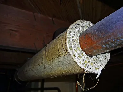 Deteriorating asbestos insulation exposed at the cut end of an old basement pipe