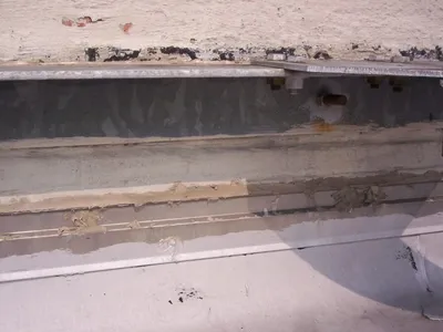 Close-up of suspect asbestos-containing material along a bolted structural beam