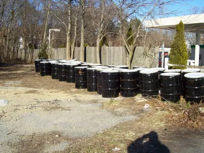 Rows of sealed black waste drums lined up at a former fueling station