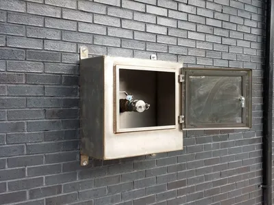 Open stainless wall cabinet housing a fuel fill valve for spill containment
