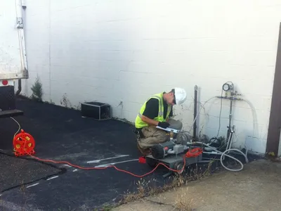 Worker recording results at a tank-testing pump and gauge setup