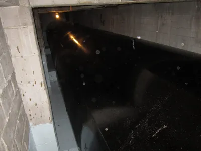 Freshly coated black storage tank inside a concrete vault
