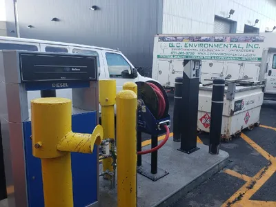 Diesel dispenser and red hose reel beside a G.C. Environmental service truck