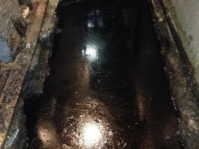 Oil-stained excavation pit cut into a basement floor during spill cleanup