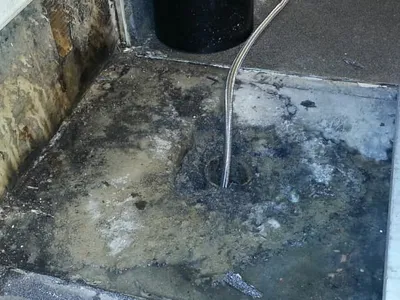 Black mold and water staining around a floor drain and downspout
