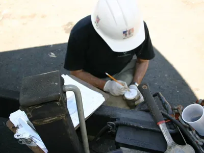 Overhead view of a technician labeling a soil sample jar with field logs and tools