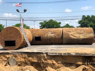 Excavated rusty storage tanks with cut access openings laid out in a lot