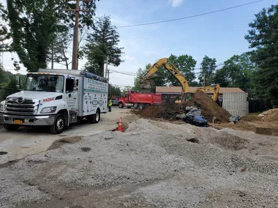 GCE HAZMAT truck on site as an excavator loads soil into a red dump truck