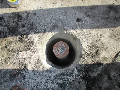 Monitoring well riser pipe set in a gravel-packed excavation before sealing