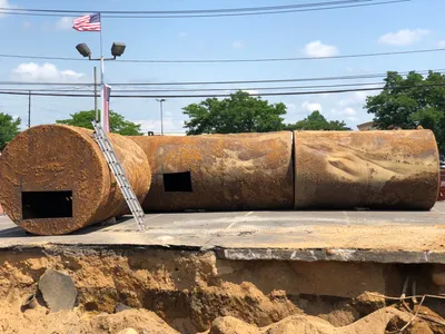 Two rusty steel tanks removed and laid beside an open excavation