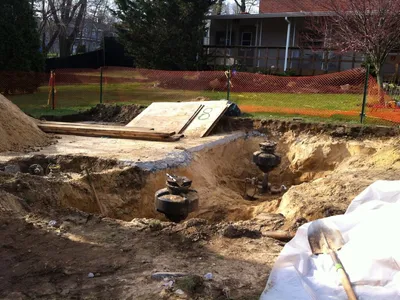 Exposed tank manways and valves in a residential backyard excavation
