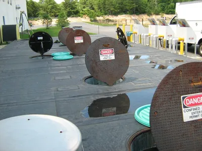 Tank pad with steel confined-space manway covers propped open for inspection