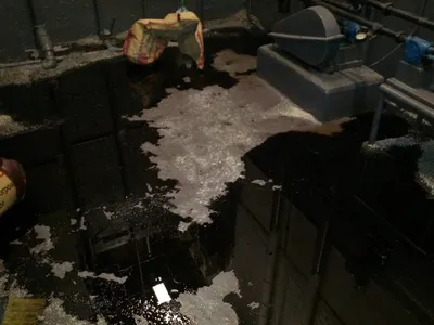 Absorbent spread over spilled oil on a dark basement floor near pumps