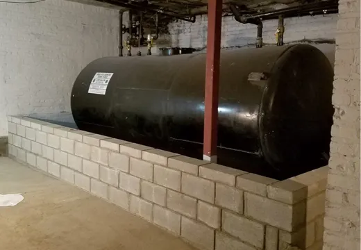 Black fuel oil tank in a basement set on a concrete-block containment dike