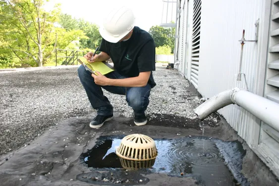 GCE inspector documenting a roof drain during a rooftop site assessment