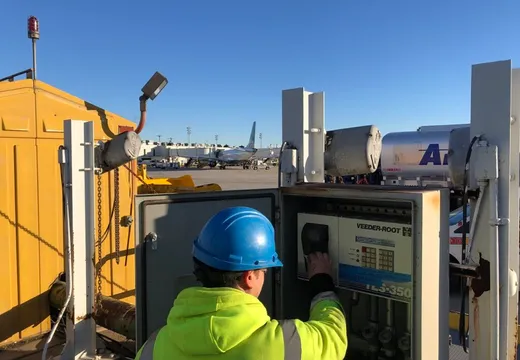 Worker operating a Veeder-Root tank monitor console on an airport ramp
