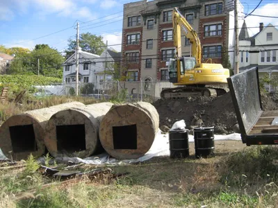 John Deere excavator and large concrete rings excavated on a vacant urban redevelopment lot