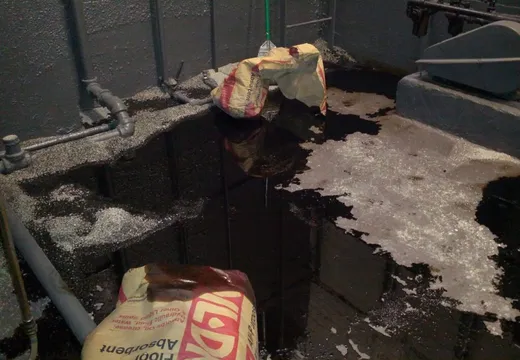 Oil spill on a basement floor treated with absorbent granules and floor-dry bags